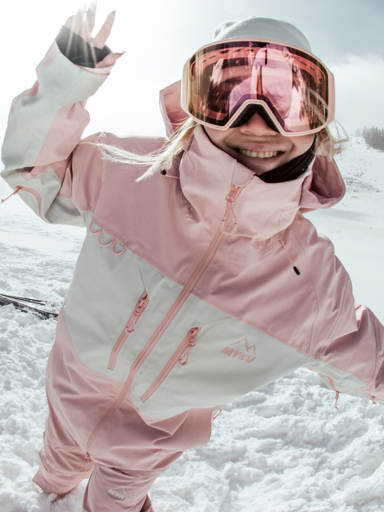 Person wearing a pink and gray snowsuit with goggles in a snowy landscape